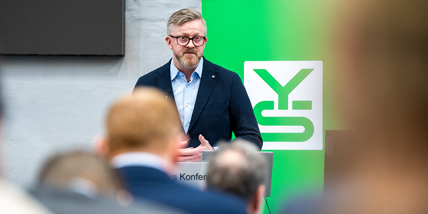 YS-leder Hans-Erik Skjæggerud foran logoen til YS
